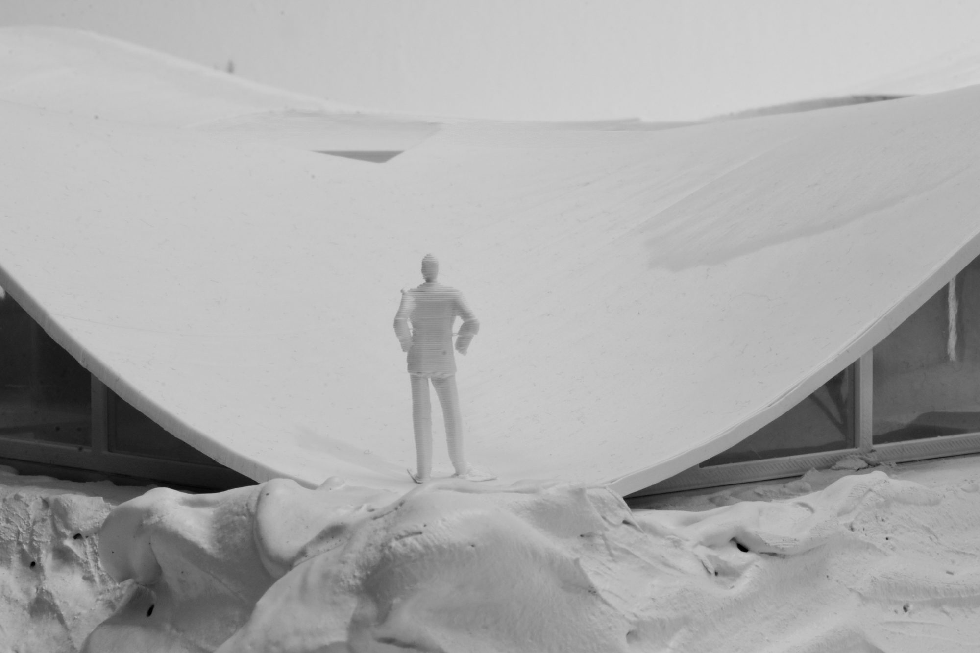 Close-up of the model: a small figure stands on the roof where it dips down to the terrain, with glazing visible on both sides.
