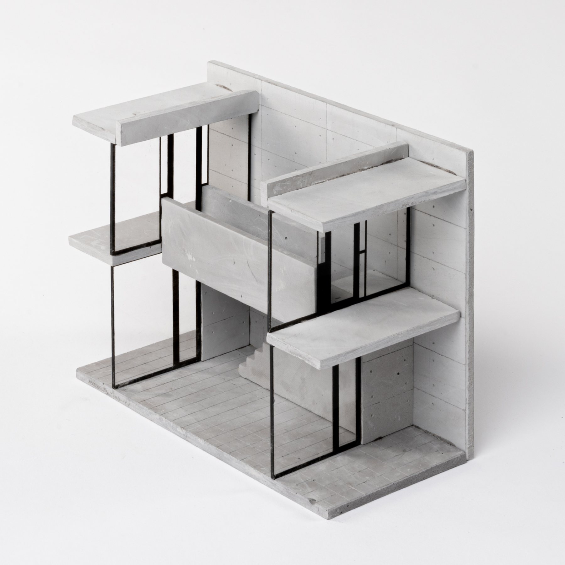 Corner view of the model: floor slabs and black-framed glazing on two levels, a solid wall behind with panel joints and tie holes, and a tiled floor.
