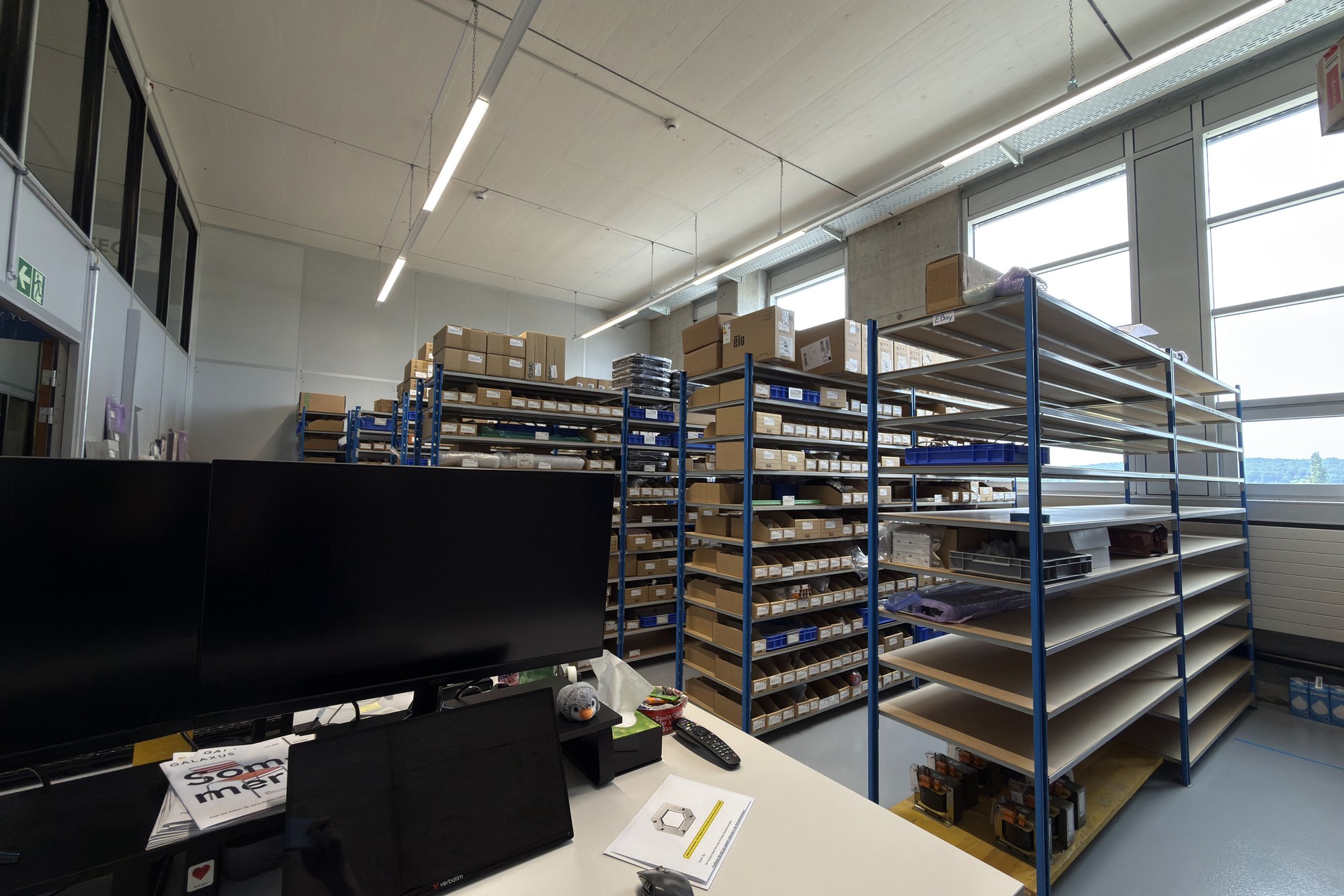 Photo of an office desk with monitors in front of the finished shelving racks.