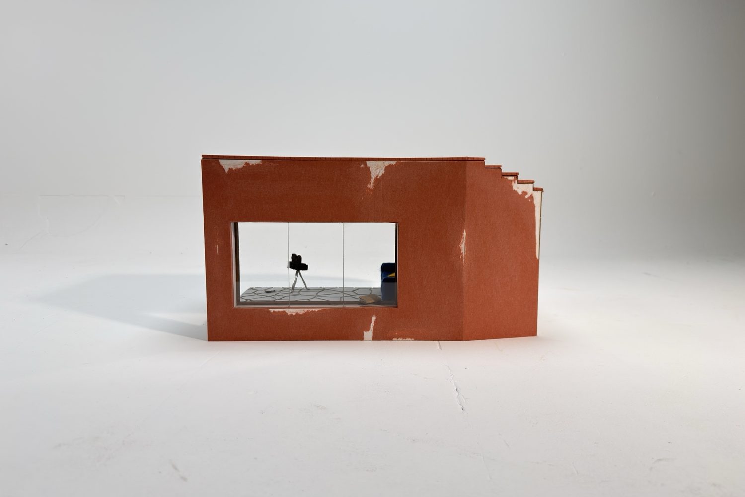 Front of the model: a terracotta-coloured wall with worn patches and a window through which the tripod and sofa can be seen.