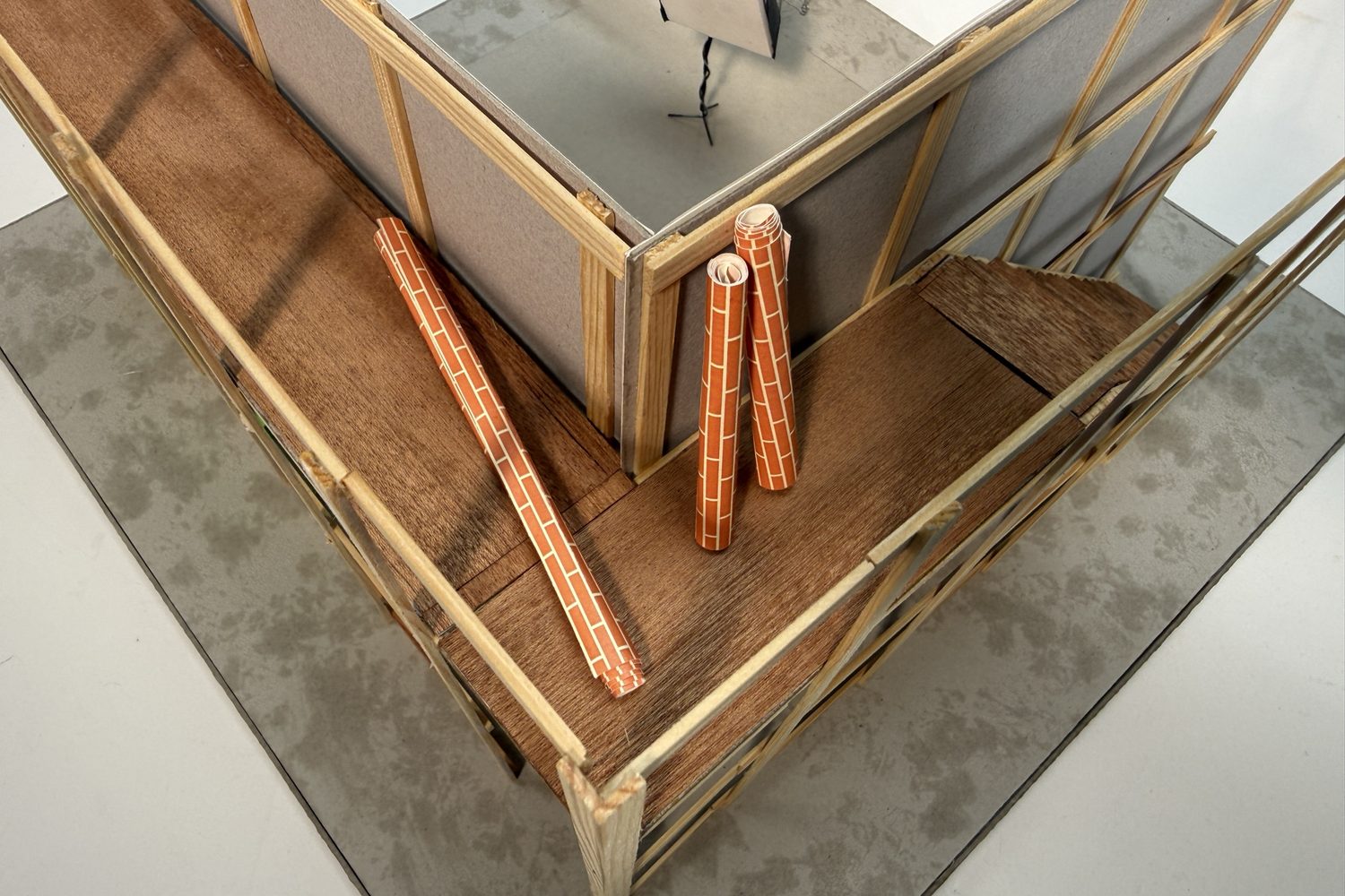 View from above of the timber frame and platform, with rolled sheets of brick paper lying on the floor.